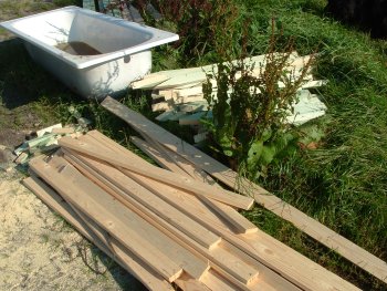 alte Badewanne und Holzleisten auf der Wiese
